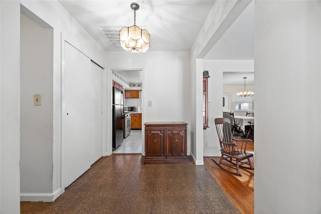 hallway featuring a chandelier and baseboards