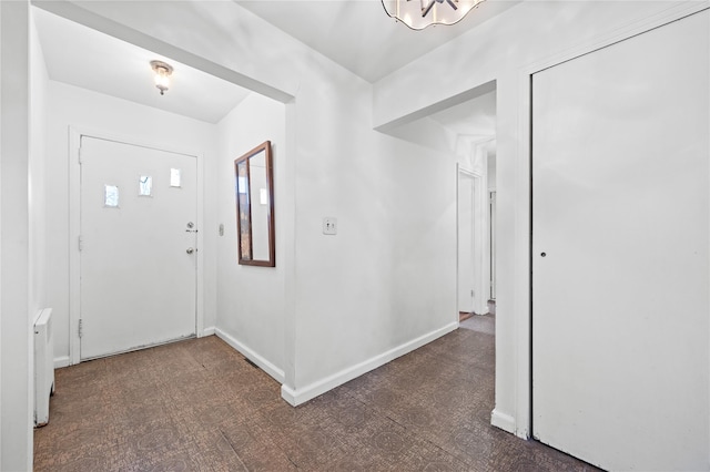 foyer featuring baseboards, a chandelier, and radiator heating unit