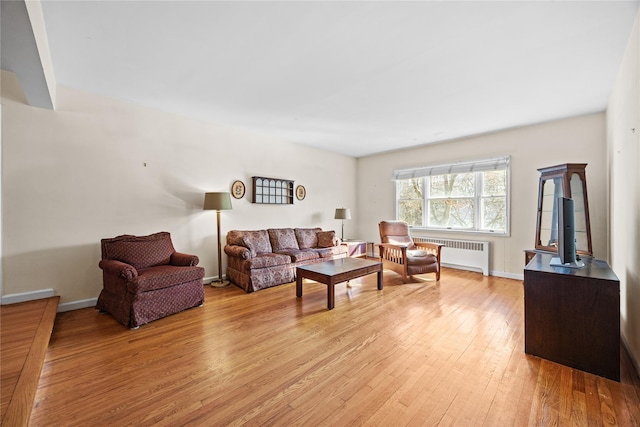 living area with light wood finished floors, radiator, and baseboards