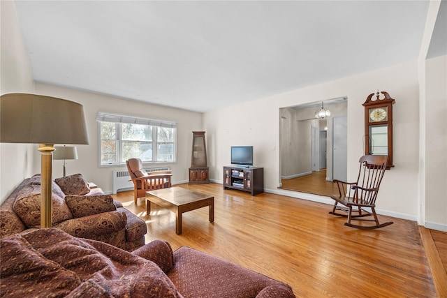 living area with radiator, baseboards, and light wood-style floors