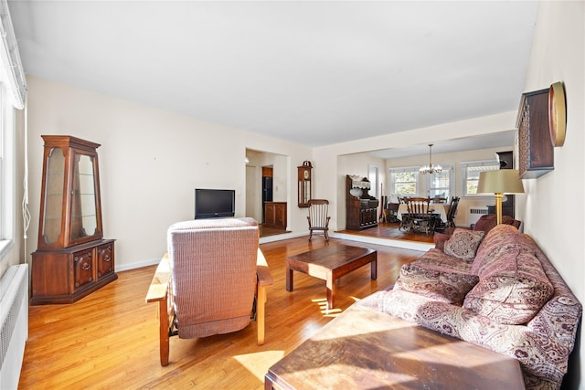 living room with light wood finished floors, a notable chandelier, and baseboards