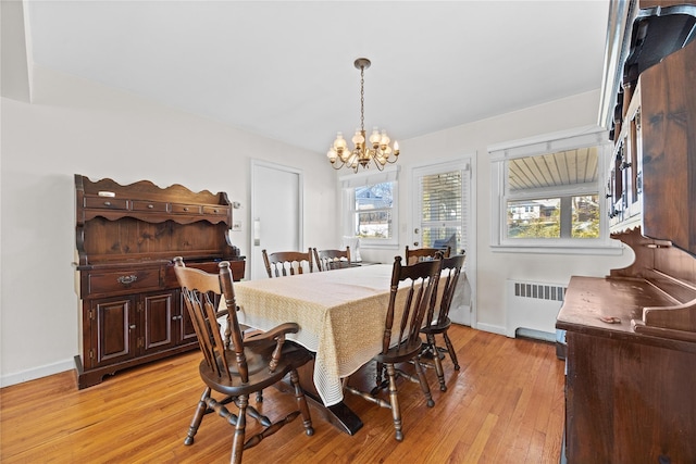 dining space with a wealth of natural light, light wood-style flooring, radiator heating unit, and an inviting chandelier