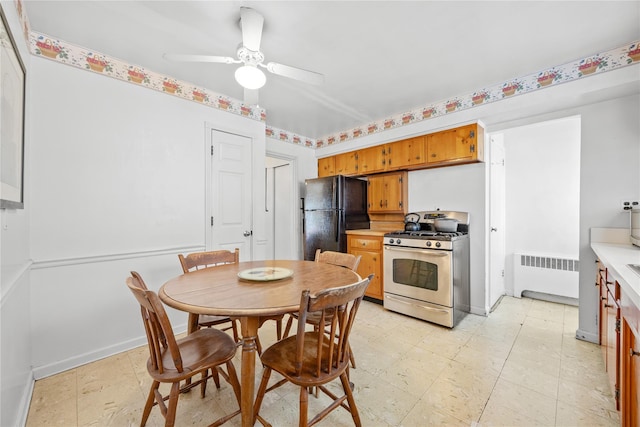 dining room with radiator heating unit, a ceiling fan, baseboards, and light floors