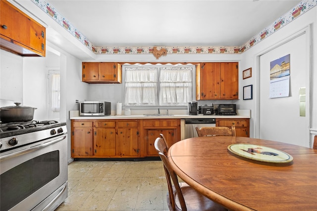 kitchen with light floors, brown cabinets, appliances with stainless steel finishes, and a sink