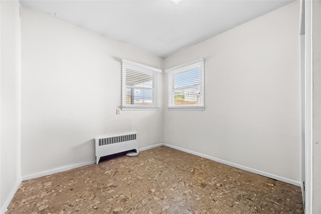 unfurnished room featuring radiator and baseboards