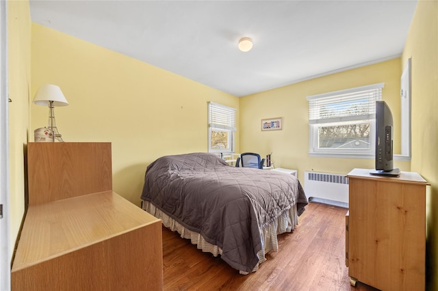 bedroom featuring wood finished floors and radiator heating unit