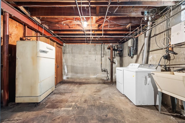 unfinished below grade area featuring washing machine and dryer and freestanding refrigerator