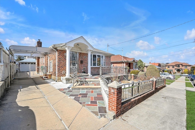 view of front of house with brick siding, a chimney, fence, and a gate