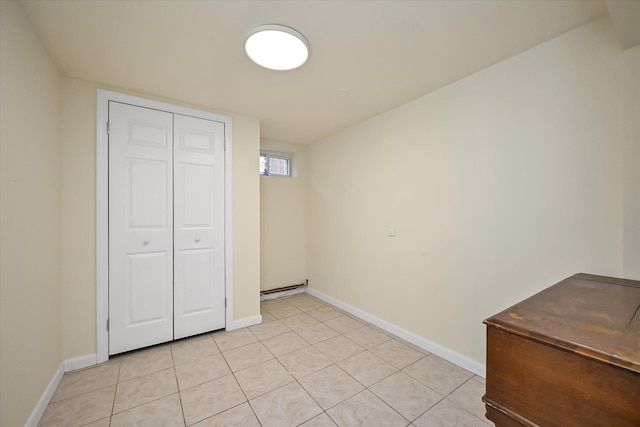 unfurnished bedroom featuring light tile patterned floors, baseboards, and a closet