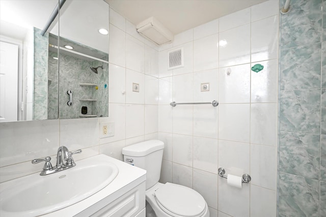 bathroom with tile walls, visible vents, toilet, vanity, and walk in shower