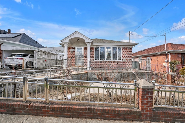 view of front of property featuring concrete driveway, a fenced front yard, a shingled roof, and brick siding