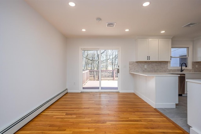 kitchen featuring a baseboard radiator, tasteful backsplash, white cabinets, and light countertops