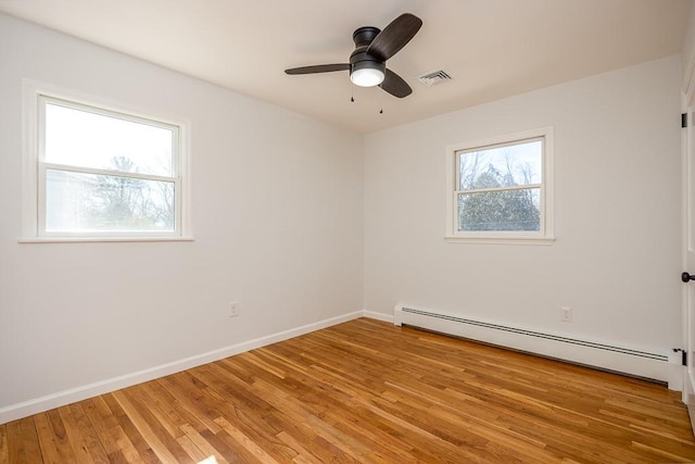 unfurnished room featuring light wood-style floors, a healthy amount of sunlight, visible vents, and a baseboard radiator