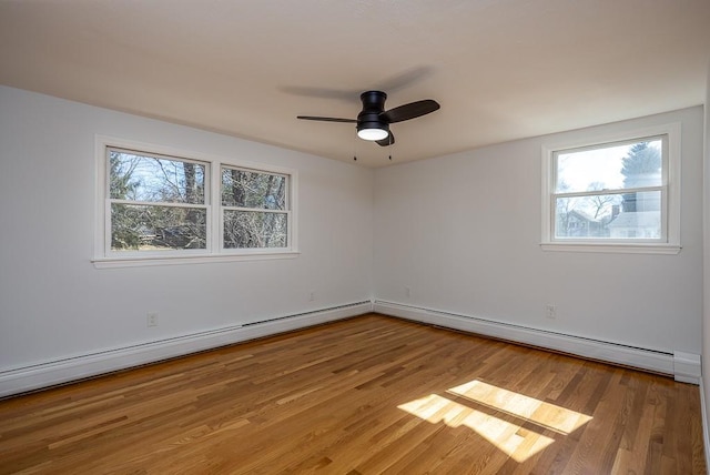 unfurnished room featuring plenty of natural light, baseboard heating, and wood finished floors