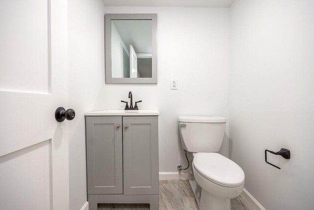 half bathroom with toilet, vanity, and baseboards