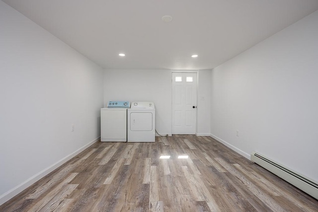 laundry area featuring a baseboard heating unit, baseboards, laundry area, wood finished floors, and separate washer and dryer