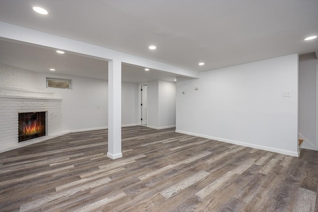 finished basement with recessed lighting, a brick fireplace, and wood finished floors