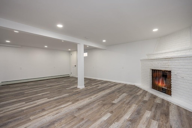 finished below grade area featuring recessed lighting, a fireplace, baseboards, and wood finished floors