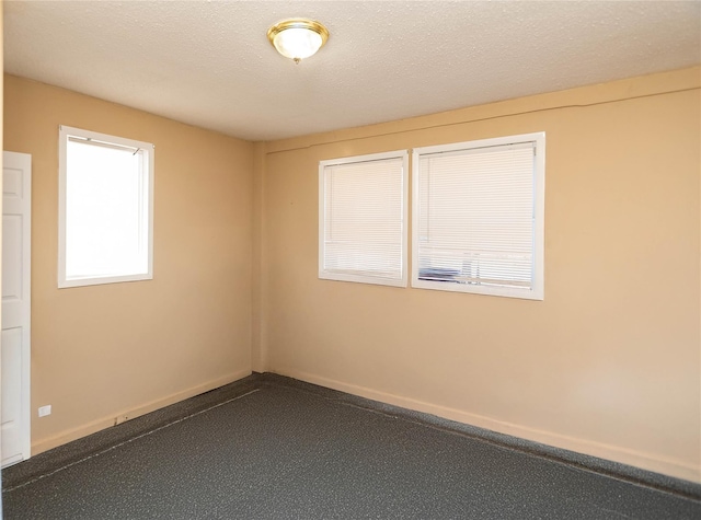 unfurnished room featuring baseboards and a textured ceiling