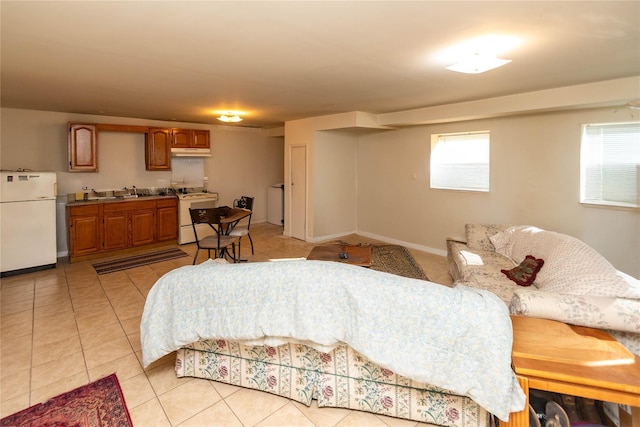 bedroom with multiple windows, light tile patterned floors, freestanding refrigerator, and a sink