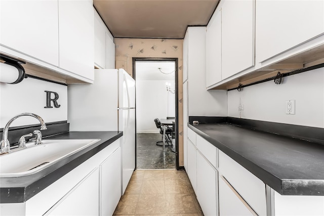 kitchen with dark countertops, white cabinets, and a sink