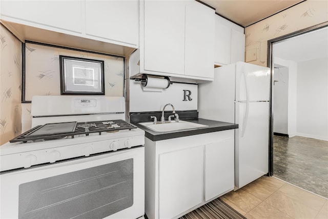 kitchen featuring dark countertops, white appliances, white cabinetry, and a sink