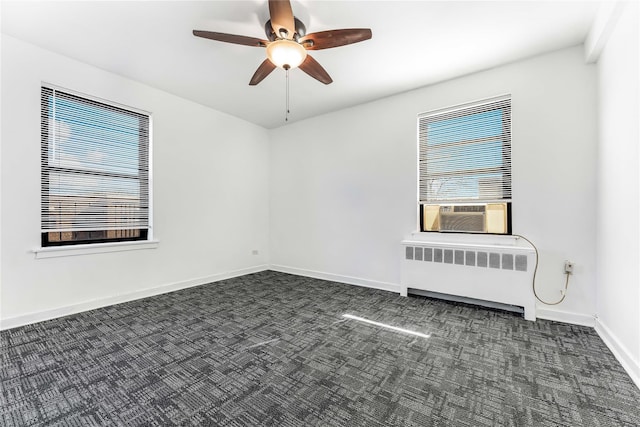 spare room featuring dark colored carpet, radiator, a ceiling fan, cooling unit, and baseboards