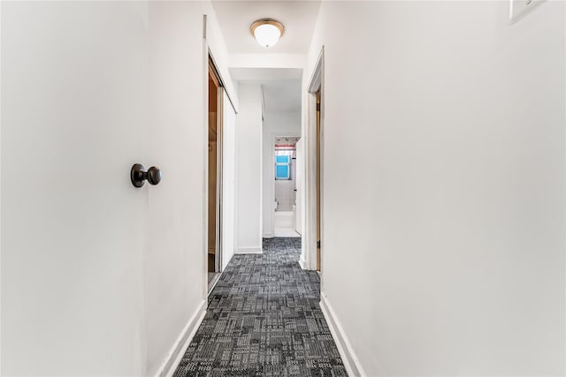 corridor with dark carpet and baseboards