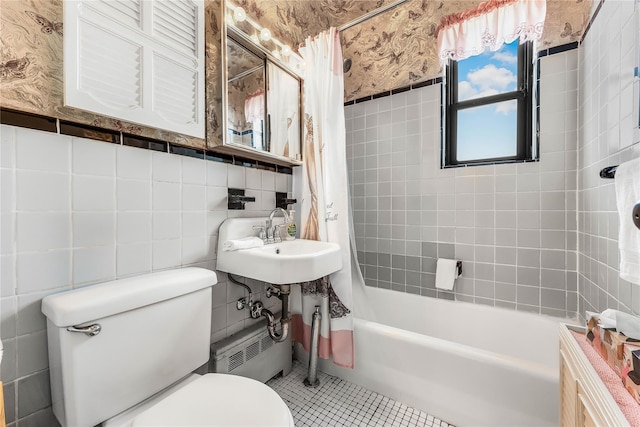 bathroom featuring wallpapered walls, tile walls, toilet, shower / bath combination with curtain, and a sink