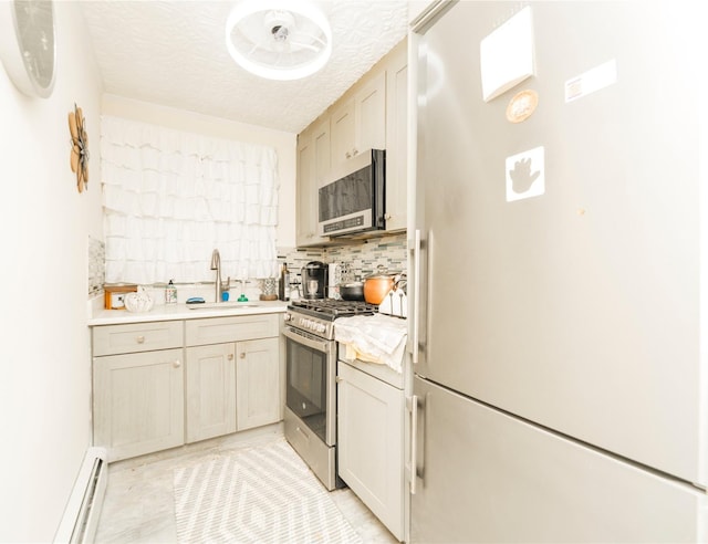 kitchen featuring a baseboard radiator, light countertops, decorative backsplash, appliances with stainless steel finishes, and a sink