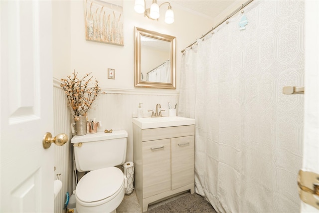 full bathroom with toilet, a wainscoted wall, and vanity