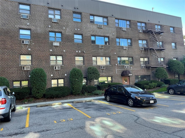 view of building exterior featuring uncovered parking and cooling unit