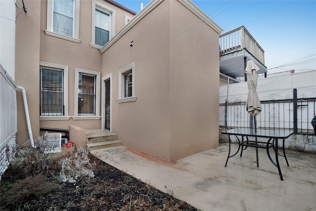 view of side of property featuring central air condition unit, a patio, and stucco siding