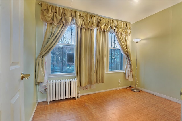 unfurnished room featuring radiator and baseboards