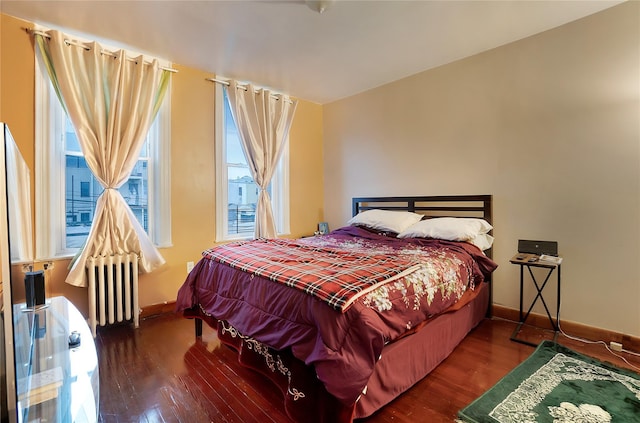 bedroom with radiator heating unit, baseboards, and wood finished floors