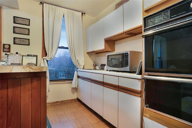 kitchen with light countertops, stainless steel microwave, white cabinetry, and dobule oven black