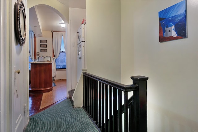 corridor featuring arched walkways and an upstairs landing