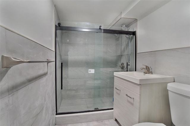 bathroom with toilet, a shower stall, tile walls, and vanity