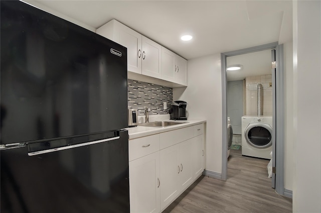 kitchen featuring tasteful backsplash, washer / clothes dryer, freestanding refrigerator, light wood-type flooring, and a sink