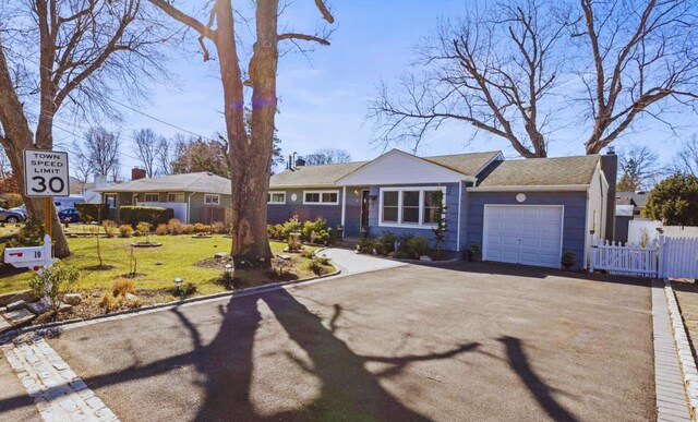 ranch-style home with a front lawn, an attached garage, driveway, and fence