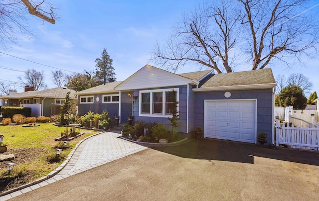 view of front of property with driveway, an attached garage, and fence