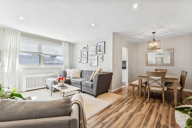 living area with recessed lighting, radiator heating unit, an inviting chandelier, light wood-style floors, and baseboards