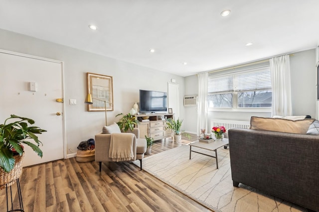 living area featuring baseboards, radiator, wood finished floors, a wall mounted air conditioner, and recessed lighting