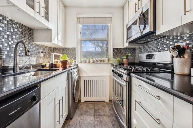 kitchen featuring appliances with stainless steel finishes, washer / dryer, white cabinetry, and a sink