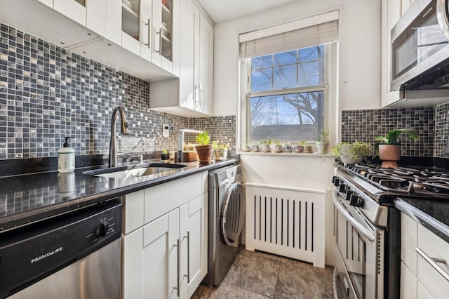 kitchen with stainless steel appliances, a sink, white cabinets, backsplash, and washer / dryer