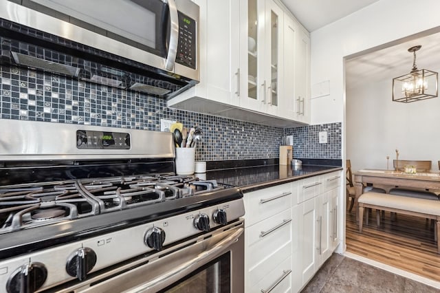 kitchen with appliances with stainless steel finishes, white cabinetry, glass insert cabinets, and tasteful backsplash