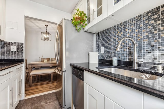 kitchen featuring stainless steel dishwasher, backsplash, a sink, and white cabinets