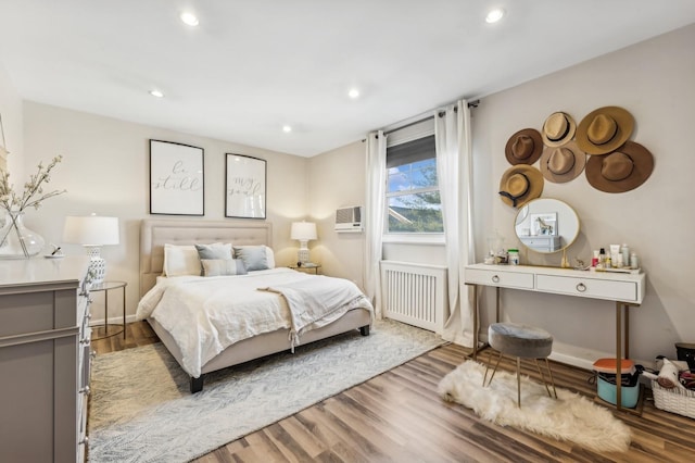 bedroom with radiator, baseboards, wood finished floors, and recessed lighting