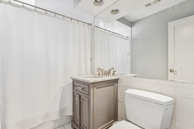 bathroom featuring vanity, toilet, and tile walls