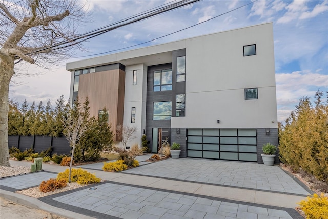 view of front of home featuring decorative driveway, an attached garage, and stucco siding